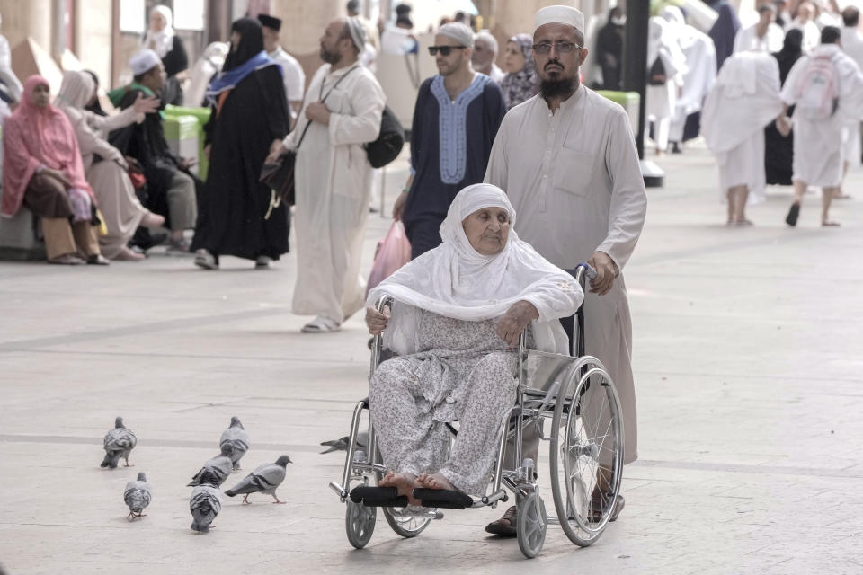 Pakistani pilgrim Gul Rehman pushes his mother on a wheel chair outside the Grand Mosque, during the annual hajj pilgrimage, in Mecca, Saudi Arabia, Saturday, June 24, 2023. Muslim pilgrims are converging on Saudi Arabia's holy city of Mecca for the largest hajj since the coronavirus pandemic severely curtailed access to one of Islam's five pillars. (AP Photo/Amr Nabil)