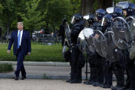El presidente Donald Trump camina frente a la policía en el Parque Lafayette después de visitar la iglesia San Juan frente a la Casa Blanca el lunes 1 de junio de 2020 en Washington. Parte de la iglesia fue incendiada durante las protestas de la noche del domingo. (AP Foto/Patrick Semansky)