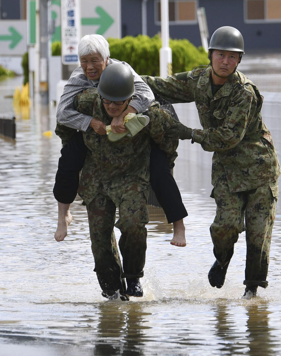 An evacuee is helped by Japan Self-Defense Forces' members as the city is hit by Typhoon Hagibis, in Motomiya, Fukushima prefecture, northern Japan, Sunday, Oct. 13, 2019. Rescue efforts for people stranded in flooded areas are in full force after a powerful typhoon dashed heavy rainfall and winds through a widespread area of Japan, including Tokyo.(Kyodo News via AP)