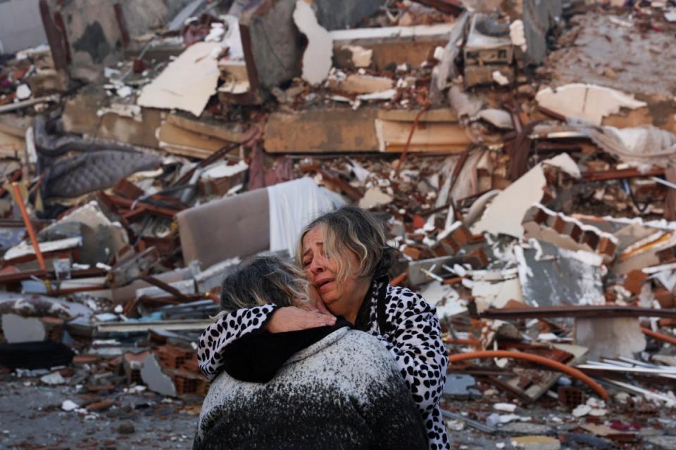 A woman reacts while embracing another person, near rubble following an earthquake in Hatay, Turkey (REUTERS)