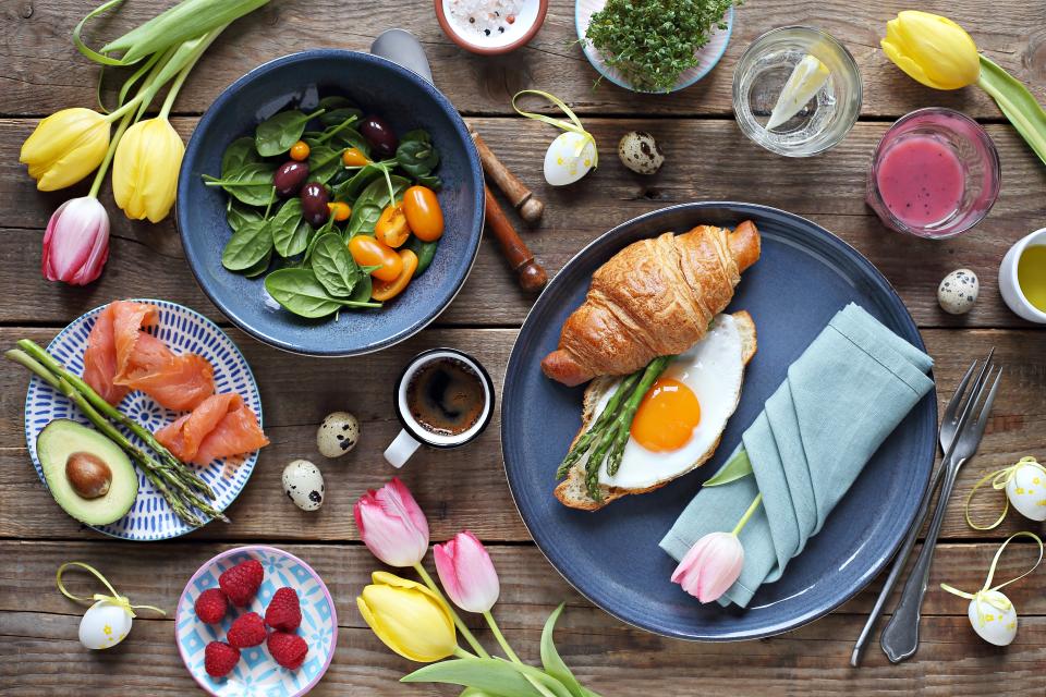 Easter festive brunch or breakfast set, meal variety with fried egg, asparagus, smoked salmon, salad bowl, avocado, croissant and smoothie. Flat layot