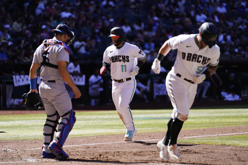 Arizona Diamondbacks' Jose Herrera (11) scores a run on a based loaded walk as Diamondbacks' Christian Walker, right, jogs to first base and Los Angeles Dodgers catcher Austin Barnes, left, pauses in front of home plate during the fifth inning of a baseball game Sunday, April 9, 2023, in Phoenix. (AP Photo/Ross D. Franklin)