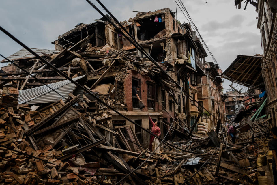 A husband passes salvaged belongings to his wife