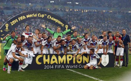 Germany's players pose for pictures as they celebrate with their World Cup trophy after winning their 2014 World Cup final against Argentina at the Maracana stadium in Rio de Janeiro July 13, 2014. REUTERS/Michael Dalder