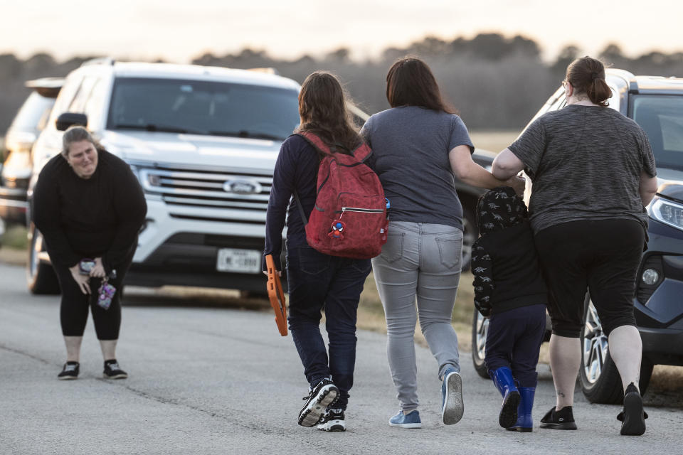 A group of women walk away from the scene where the bodies of three teenagers were found dead inside of a home Tuesday, Jan. 18, 2022, in Crosby, Texas, about 25 miles (40.23 kilometers) northeast of Houston. Authorities said it appears one of the teens killed themself after killing the other two. (Brett Coomer/Houston Chronicle via AP)