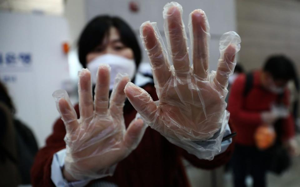 A South Korean woman wearing plastic gloves at the Incheon International Airport - Getty Images AsiaPac