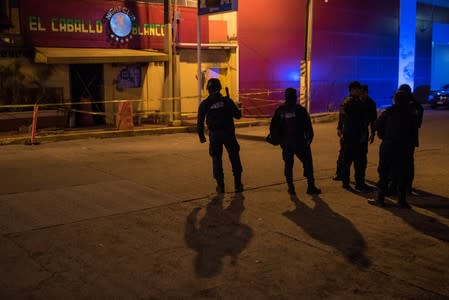 Police officers keep watch outside the "El Caballo Blanco" bar following a deadly arson attack by suspected gang members, in Coatzacoalcos