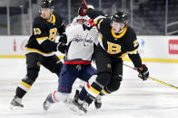 Boston Bruins' Brandon Carlo (25) checks Washington Capitals' Jakub Vrana, center, during the first period of an NHL hockey game Friday, March 5, 2021, in Boston. (AP Photo/Michael Dwyer)