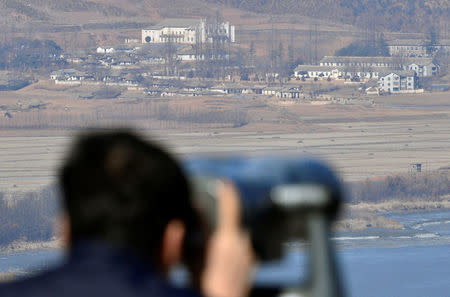 A man looks towards North Korea's propaganda village Kaepoong through a pair of binoculars from an observation platform, near the demilitarized zone separating the two Koreas in Paju, South Korea, February 12, 2017. Shin Woong-su/News1 via REUTERS