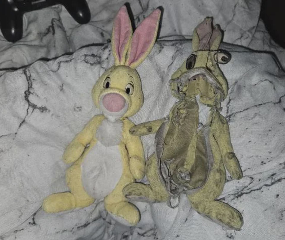 Two plush rabbits: one in good condition, the other is very worn and has no facial features. They are lying on a blanket