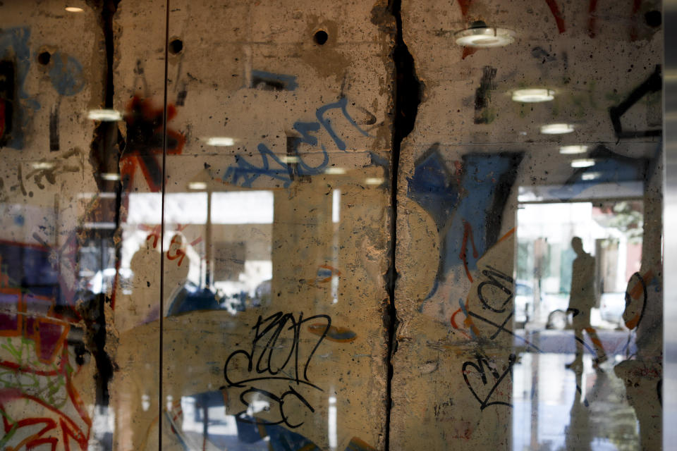 In this Thursday, Sept. 26, 2019 photo a man is reflected in a glass protecting a segment of the Berlin Wall at Editorial Perfil in Buenos Aires, Argentina. (AP Photo/Natacha Pisarenko)