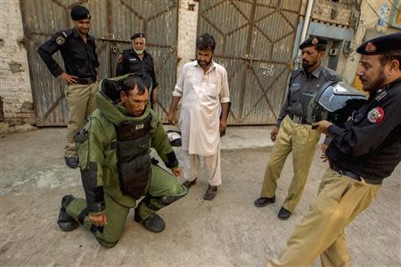 A technician from Pakistan's top bomb disposal unit kneels down to rest, due to wearing a heavy protective suit, during a bomb search operation in Peshawar October 2, 2013. REUTERS/Zohra Bensemra