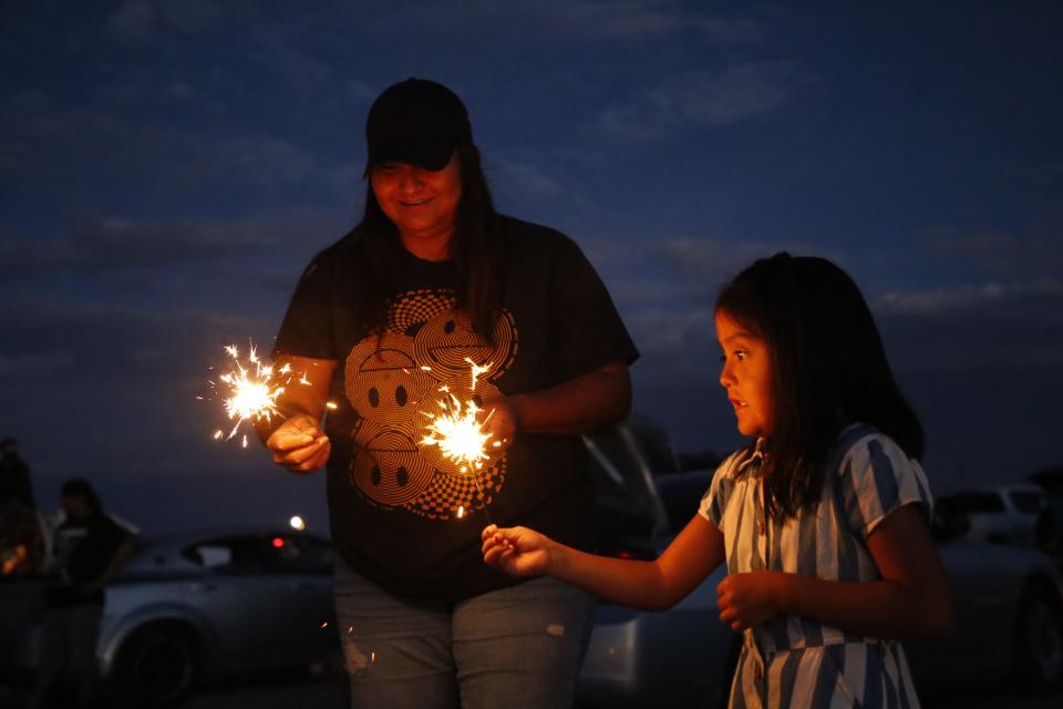 Toadlena residents Denise Corujo, left, and her daughter, Cadence James, burn sparklers while waiting for the fireworks show to start on July 1 in Shiprock.