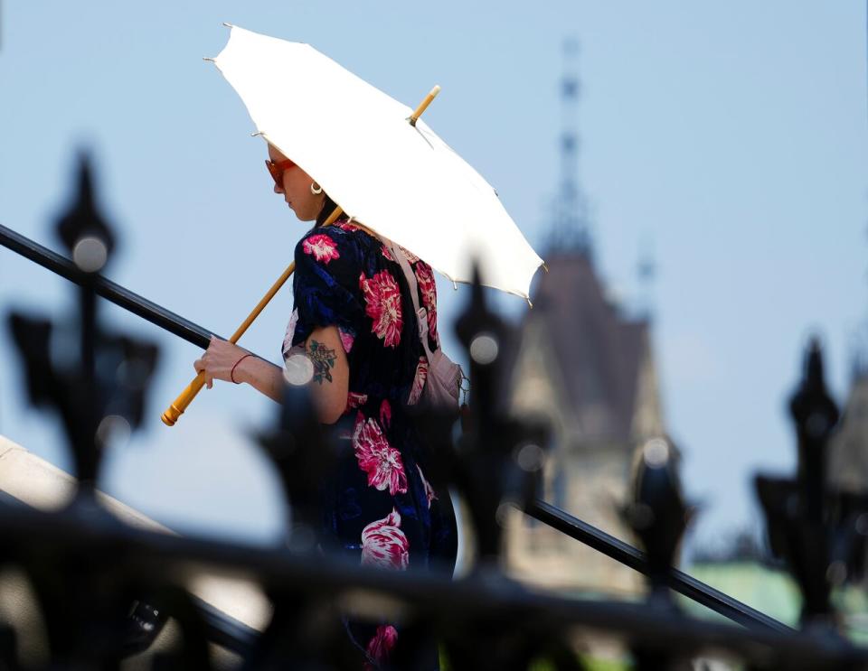 A person carries an umbrella for shade as they walk on Parliament Hill in Ottawa on Tuesday, June 18, 2024, as temperatures hit 32C in what meteorologists are calling a heat dome. 