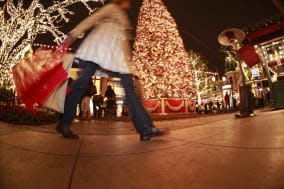 Pedestrian with shopping bags walking in downtown shopping area at Christmas