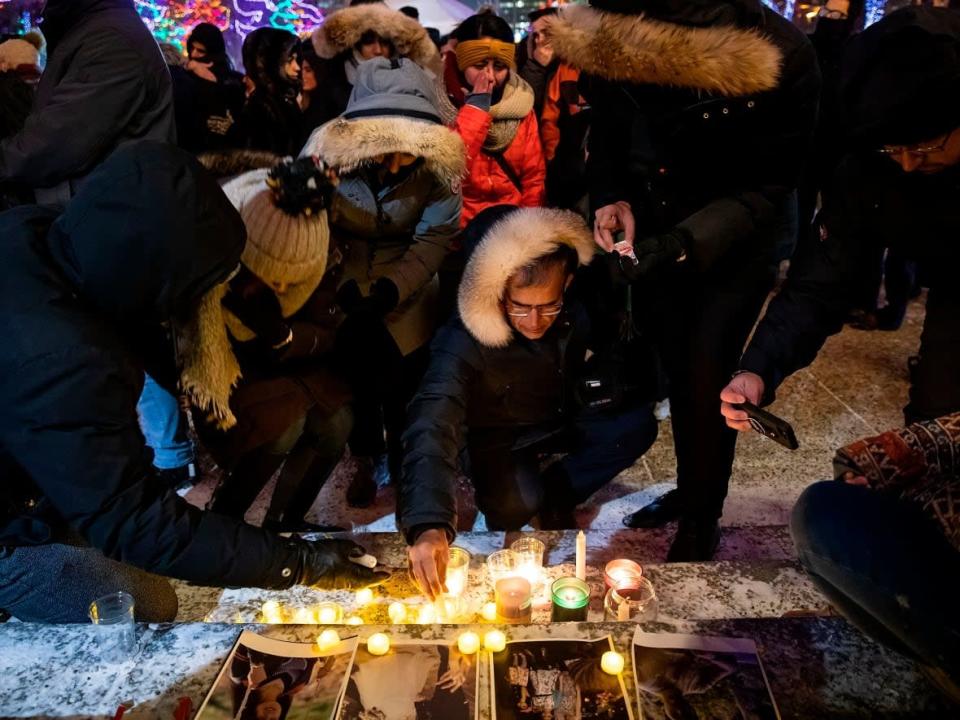 Outside the Alberta legislature building in Edmonton on Jan. 8, 2020, mourners place candles and photographs at a vigil for those killed aboard Ukraine International Airlines Flight PS752. (Codie McLachlan/Canadian Press  - image credit)