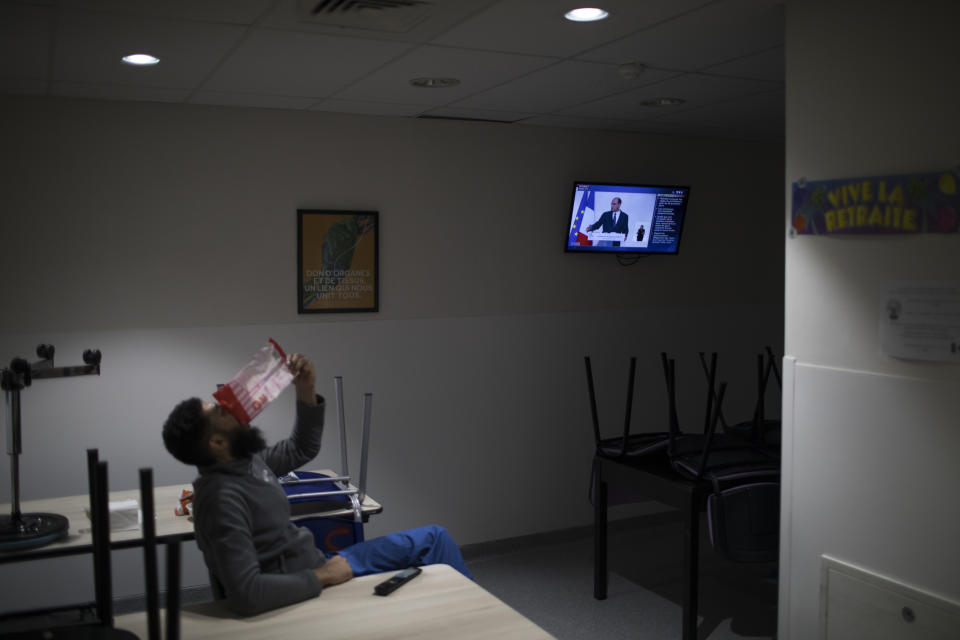 A nurse finishes a snack as a speech by French Prime Minister Jean Castex is played on the news in the ICU break room at the La Timone hospital in Marseille, southern France, Thursday, Nov. 12, 2020. Marseille has been submerged with coronavirus cases since September. The port city, on France's Mediterranean coast, was spared the worst of the virus last spring only to be hit with a vengeance as the summer vacation wound down. (AP Photo/Daniel Cole)