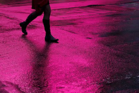 A woman walks in silhouette across a rain soaked 7th avenue in New York February 24, 2016. REUTERS/Shannon Stapleton