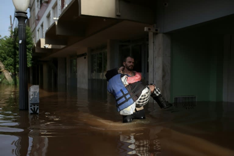Un voluntario lleva en brazos a Carmelina Castro, una mujer de 79 años, por una calle inundada del barrio de Cidade Baixa, el 8 de mayo de 2024 en Porto Alegre, al sur de Brasil (Anselmo Cunha)