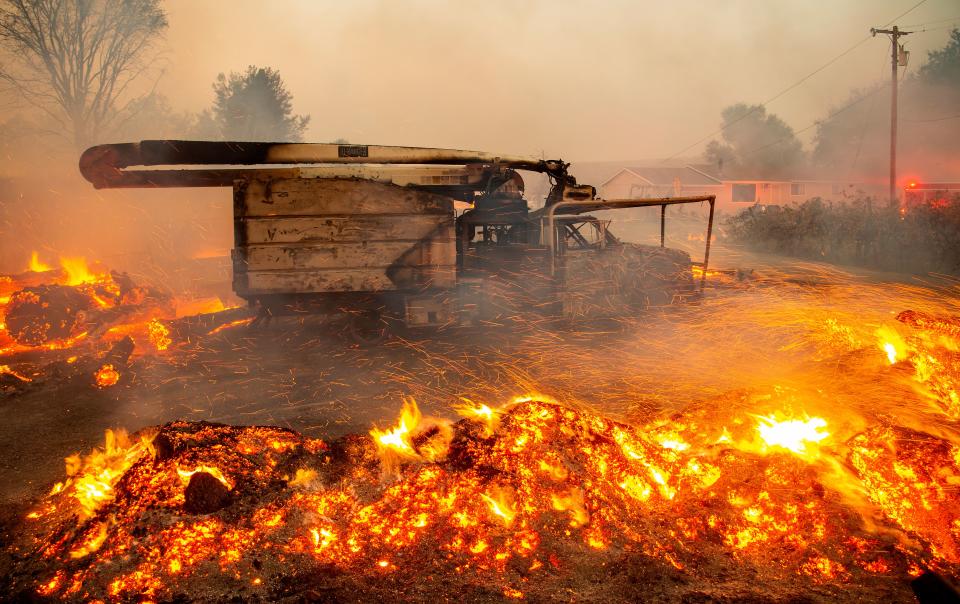 Fire and embers blow around a burnt utility truck during the Kincade fire in Healdsburg, California on October 27, 2019. - Powerful winds were fanning wildfires in northern California in "potentially historic fire" conditions, authorities said October 27, as tens of thousands of people were ordered to evacuate and sweeping power cuts began in the US state. (Photo by Josh Edelson / AFP) (Photo by JOSH EDELSON/AFP via Getty Images)