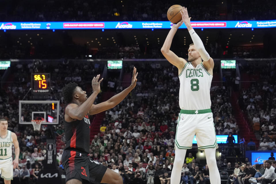 Boston Celtics center Kristaps Porzingis (8) aims a three-point basket over Miami Heat center Thomas Bryant (31)during the first half of an NBA basketball game, Thursday, Jan. 25, 2024, in Miami. (AP Photo/Marta Lavandier)