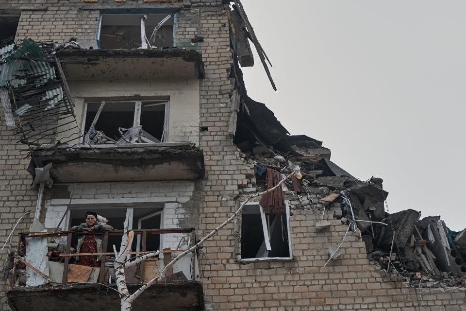 An elderly civilian woman stands with a cat on the balcony of her destroyed house in the city of Avdiivka (Getty Images)