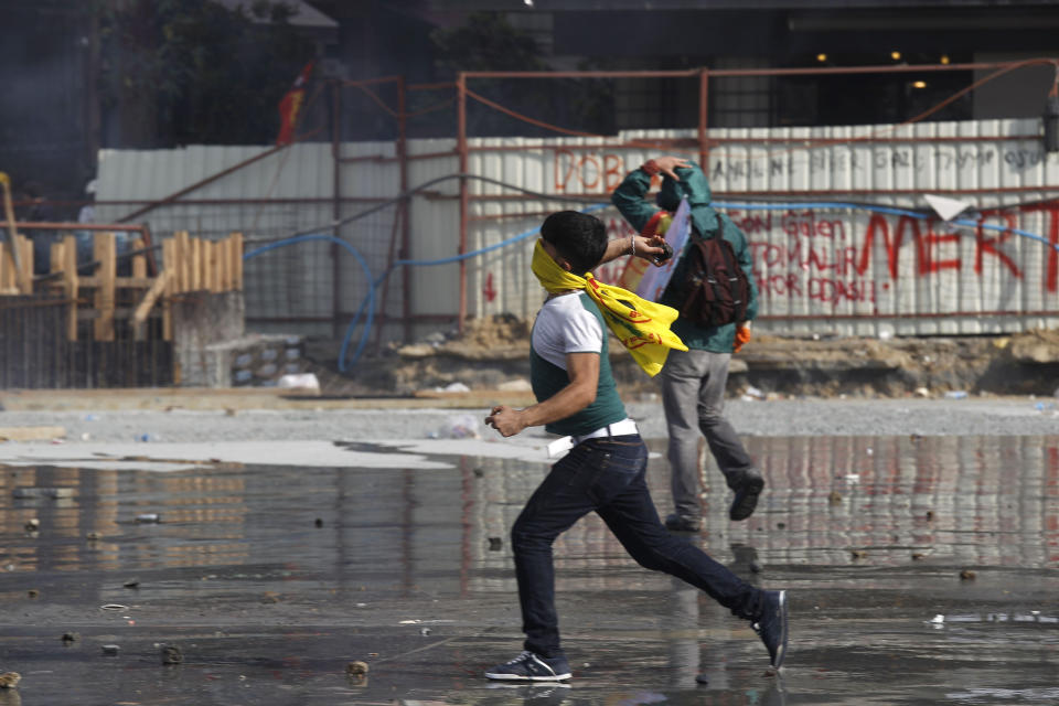 A protester throws a stone towards riot policemen during clashes in Taksim Square in Istanbul, Turkey, Tuesday, June 11, 2013. Hundreds of police in riot gear forced through barricades in Istanbul's central Taksim Square early Tuesday, pushing many of the protesters who had occupied the square for more than a week into a nearby park. (AP Photo/Kostas Tsironis)