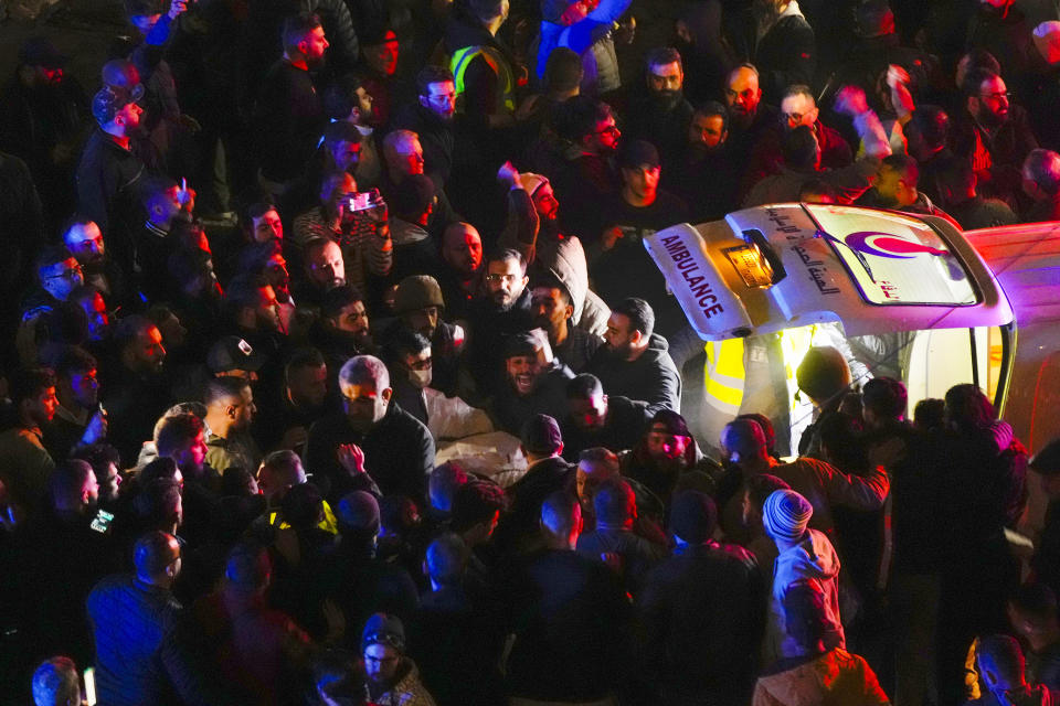 People carry a body following a massive explosion in the southern suburb of Beirut, Lebanon, Tuesday, Jan. 2, 2024. (AP Photo/Hassan Ammar)