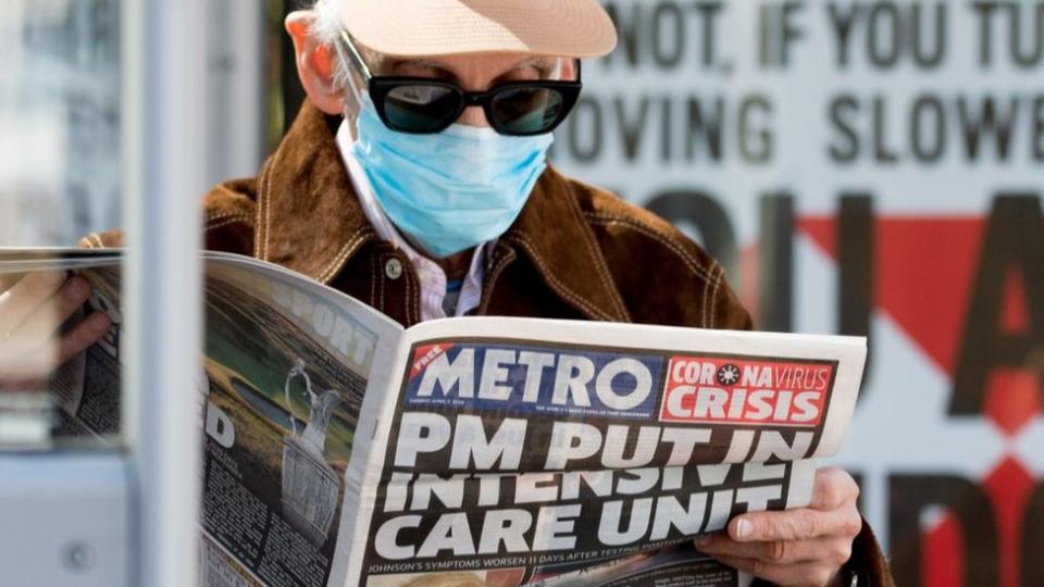 Un hombre con tapaboca lee un diario en Reino Unido