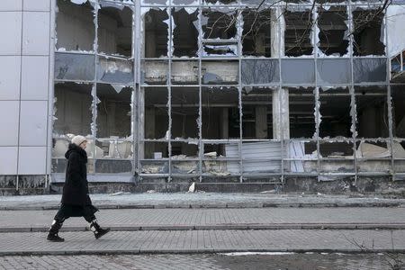 A woman walks by a building, which was damaged by shelling last September, in Donetsk, February 15, 2015. REUTERS/Baz Ratner