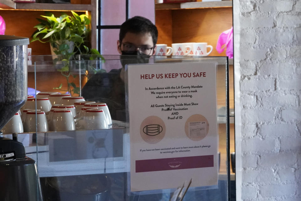 A sign explaining the LA County Mandate is posted for customers inside the Intelligentsia Coffee on Sunset Blvd., in Los Angeles, Monday, Nov. 29, 2021. Enforcement began Monday in Los Angeles for one of the strictest vaccine mandates in the country, a sweeping measure that requires proof of COVID-19 shots for everyone entering a wide variety of businesses from restaurants to theaters and gyms to nail and hair salons. (AP Photo/Damian Dovarganes)