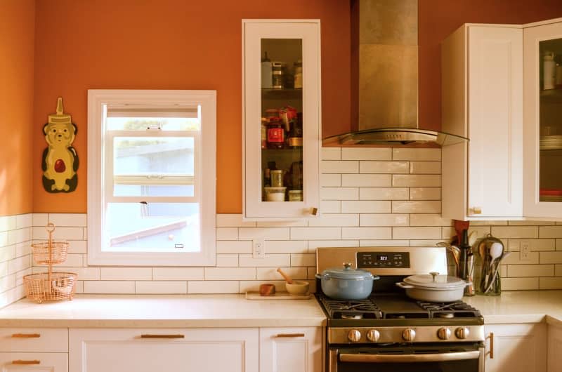 White countertop and cabinets line orange kitchen