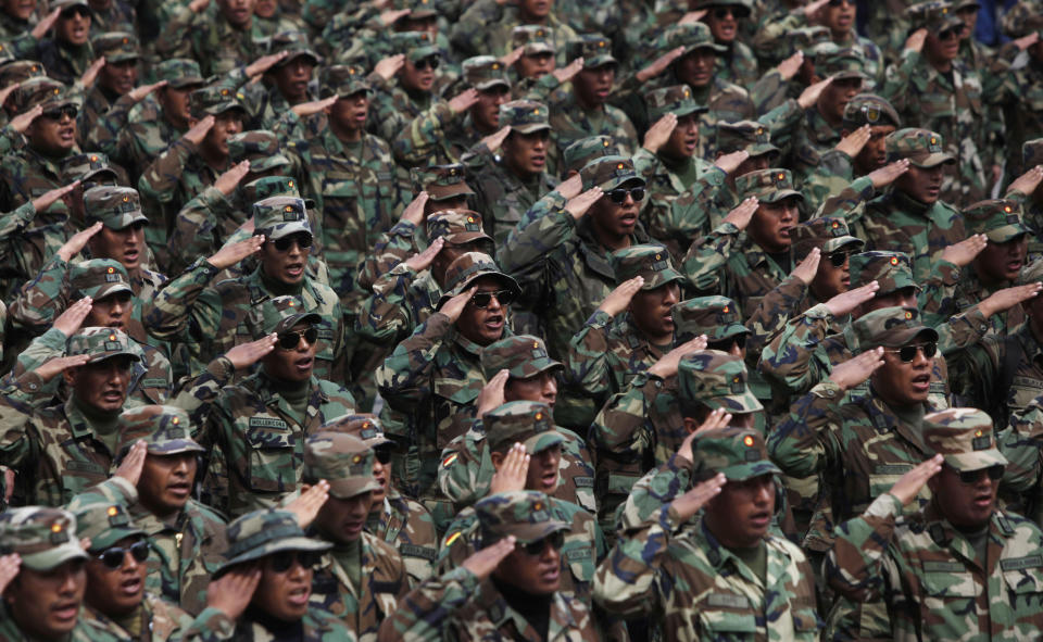 Soldados del ejército boliviano saludan cuando cantan el himno patrio en una nueva marcha de protesta callejera en La Paz, Bolivia, el jueves 24 de abril de 2014. (AP foto/Juan Karita)