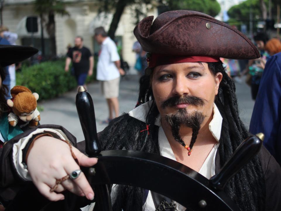 A woman dressed as Jack Sparrow steers a wheel