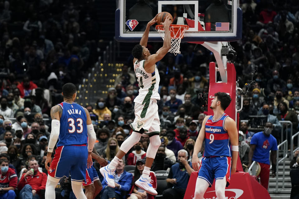 Milwaukee Bucks forward Giannis Antetokounmpo, of Greece, dunks on Washington Wizards forwards Kyle Kuzma, bottom left, and Deni Avdija, of Israel, in the second half of an NBA basketball game, Sunday, Nov. 7, 2021, in Washington. (AP Photo/Patrick Semansky)