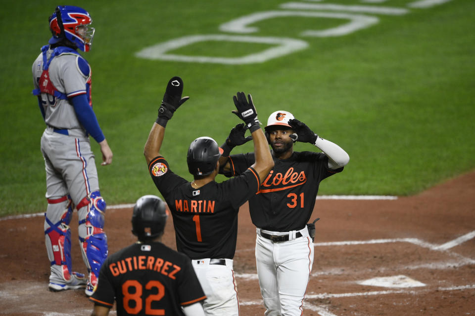 Baltimore Orioles' Cedric Mullins (31) celebrates his three-run home run with Richie Martin (1) and Kelvin Gutierrez (82) during the second inning of a baseball game against the Texas Rangers, Friday, Sept. 24, 2021, in Baltimore. Rangers catcher Jonah Heim, top left, looks on. (AP Photo/Nick Wass)