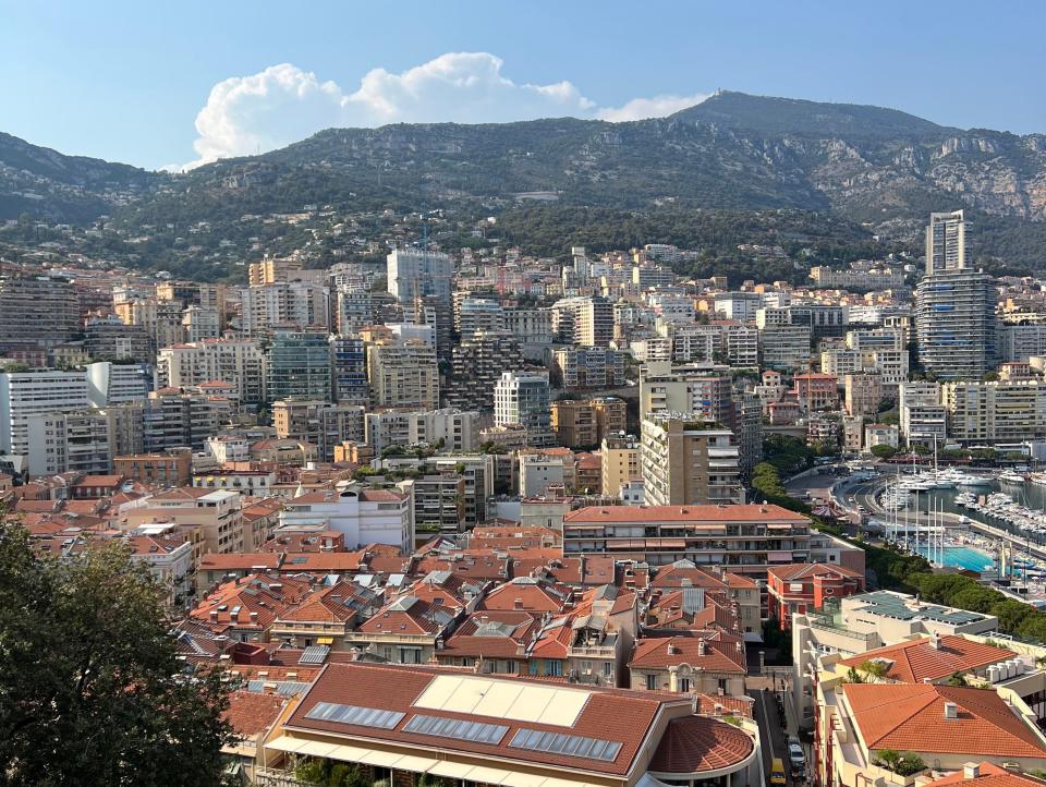 The skyline and roofs of buildings set against the mountains with a blue sky in Monte Carlo, Monaco.