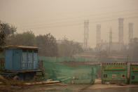 A private security guard is seen behind a mesh screen at a construction site enveloped in smog and dust in New Delhi, India, Wednesday, Nov. 4, 2020. The national capital, one of the world’s most polluted cities, enjoyed a respite from air pollution up until September in part thanks to a virus lockdown. But with industrial activities resuming and cars back on the roads — along with the onset of cooler weather and less wind, air quality in the city has once again fallen to unhealthy levels. (AP Photo/Altaf Qadri)