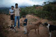 Nery Flores, 22, and his wife, Ada Castron, 19, stand with their son, Daniel Flores, 3, at the site of their home destroyed by a landslide triggered by hurricanes Eta and Iota in the village of La Reina, Honduras, Saturday, June 26, 2021. No one died. But seven months later, La Reina’s people remain homeless, and adrift. (AP Photo/Rodrigo Abd)