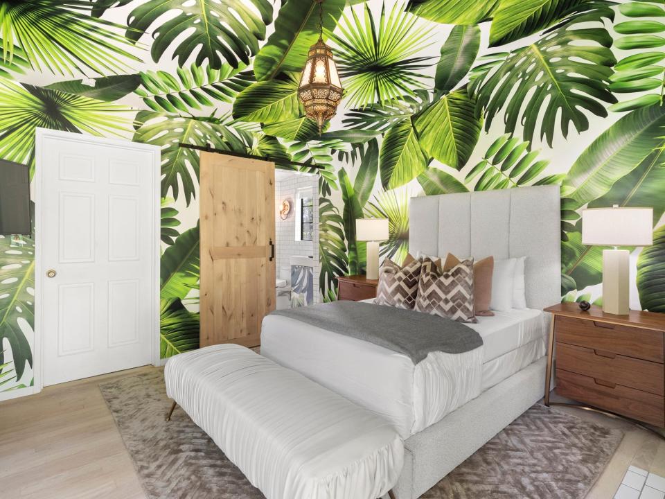 A room painted with palm fronds and a small white bed