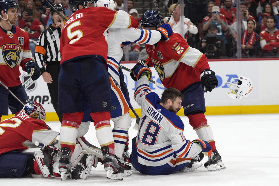 Edmonton Oilers left wing Zach Hyman (18) loses his helmet as a scuffle breaks out during the second period of Game 1 of the team's NHL hockey Stanley Cup Finals against the Florida Panthers, Saturday, June 8, 2024, in Sunrise, Fla. (AP Photo/Wilfredo Lee)