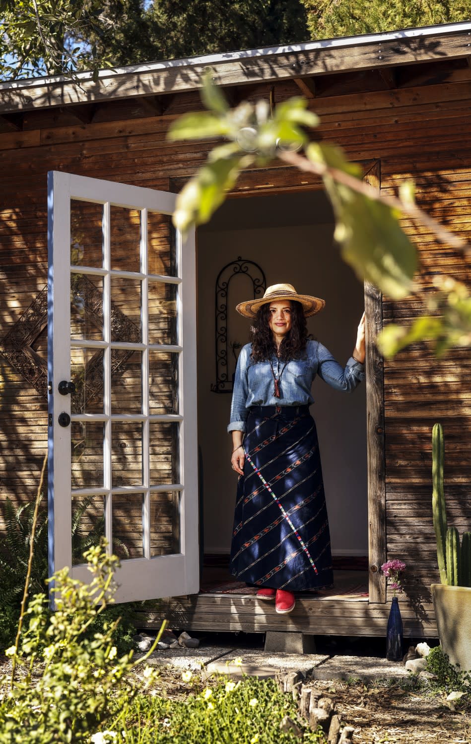 A woman stands in a doorway of a wooden structure