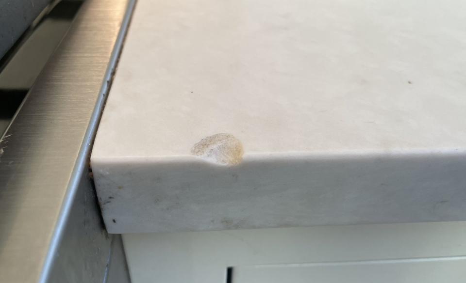 a quartz countertop with a chip in its edge, likely caused by a heavy cast iron pan