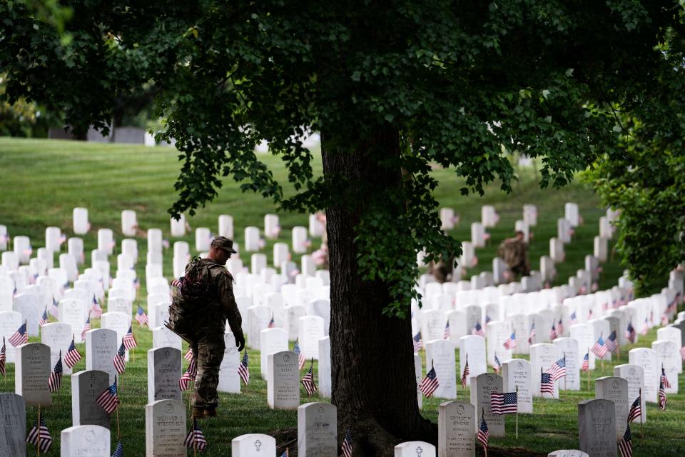 A member of the 3rd U.S. Infantry Regiment walks along a row or headstones during a joint service “Flags-In” ceremony at Arlington National Cemetery on Thursday, May 25, 2023