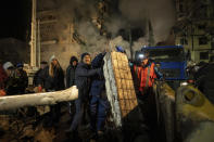 Local residents clear the rubble after a Russian rocket hit a multistory building leaving many people under debris in the southeastern city of Dnipro, Ukraine, Saturday, Jan. 14, 2023. (AP Photo/Evgeniy Maloletka)