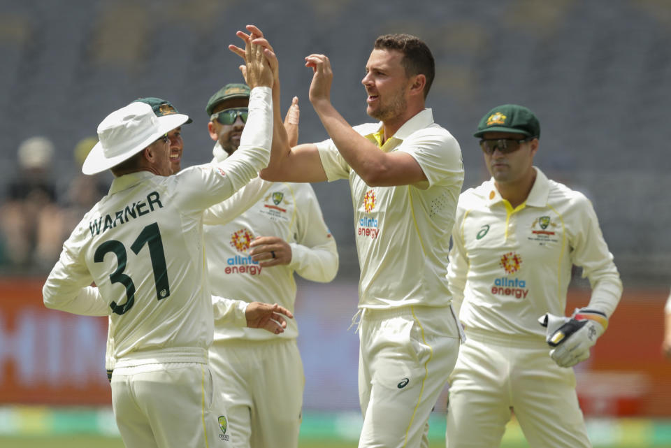 Australia's Josh Hazlewood, centre, is congratulated bye teammate David Warner after taking the wicket of West Indies' Tagenarine Chanderpaul during play on the third day of the first cricket test between Australia and the West Indies in Perth, Australia, Friday, Dec. 2, 2022. (AP Photo/Gary Day)