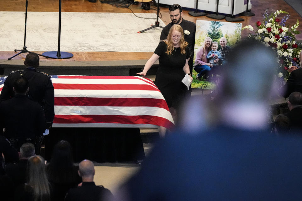 Widow of Officer Joshua Eyer, Ashley, Eyer is escorted to her seat after speaking during a memorial service for Officer Joshua Eyer, Friday, May 3, 2024, in Charlotte, N.C.Police in North Carolina say a shootout that killed Eyer and wounded and killed other officers began as officers approached a home to serve a felony warrant on Monday. (AP Photo/Chris Carlson)