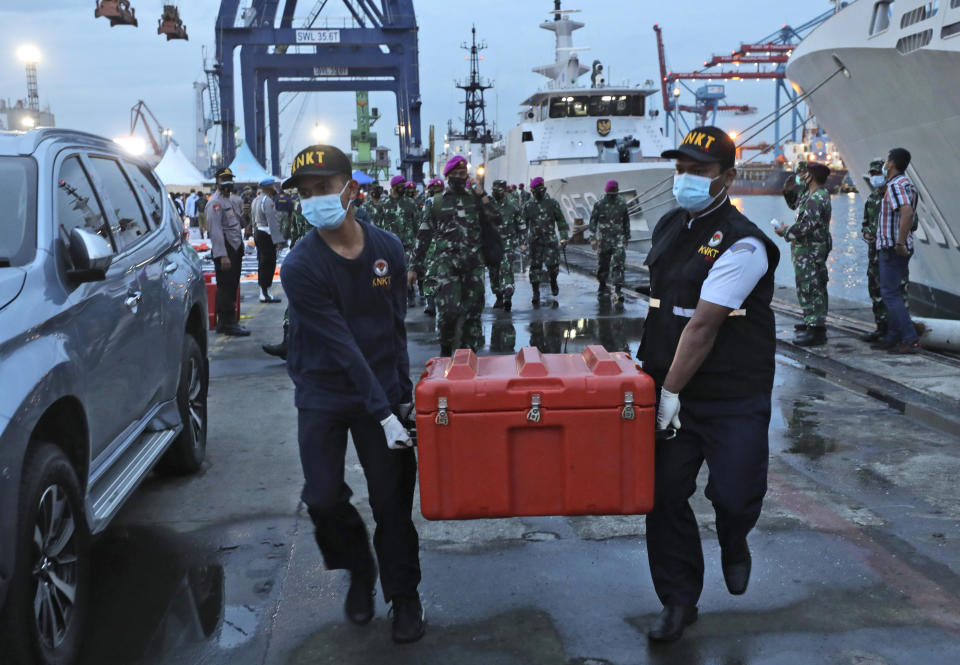 Members of the National Transportation Safety Committee carry a box containing the flight data recorder of Sriwijaya Air flight SJ-182 retrieved from the Java Sea where the passenger jet crashed at the Tanjung Priok Port, Tuesday, Jan. 12, 2021. Indonesian navy divers searching the ocean floor on Tuesday recovered the flight data recorder from a Sriwijaya Air jet that crashed into the Java Sea with 62 people on board, Saturday, Jan. 9, 2021. (AP Photo/Dita Alangkara)