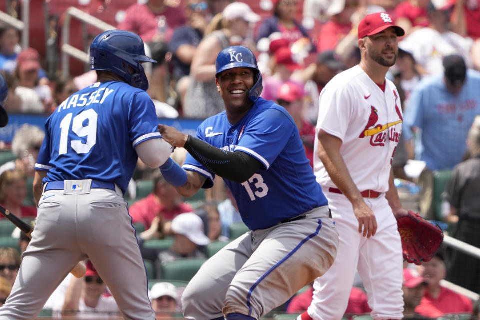 Kansas City Royals' Salvador Perez (13) is helped up by teammate Michael Massey (19) after scoring as St. Louis Cardinals starting pitcher Adam Wainwright, right, walks past during the fifth inning of a baseball game Monday, May 29, 2023, in St. Louis. (AP Photo/Jeff Roberson)