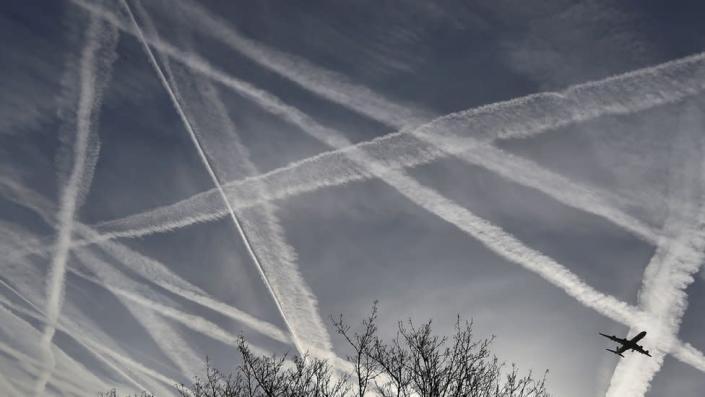 Traînées se croisant dans le ciel et avion visible